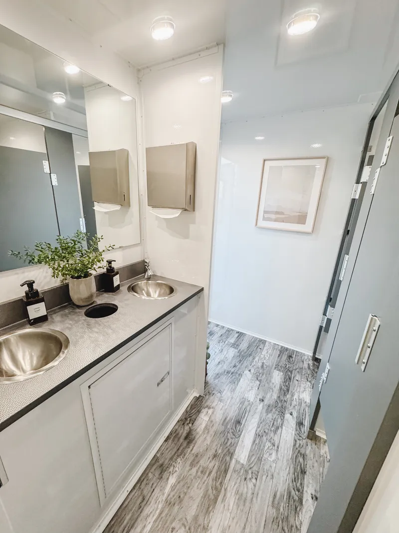 view showing sinks, stalls, and light coming from open door